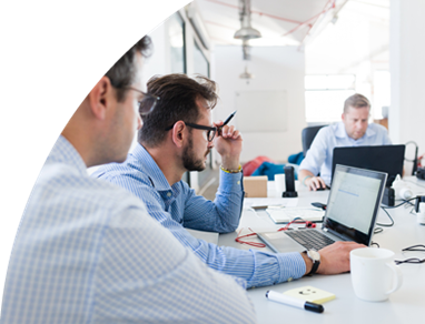 Mehrere Personen sitzen an einem Tisch, arbeiten an Laptops und tauschen Ideen aus.